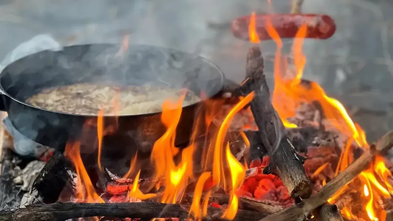 Matlagning över öppen eld, en härlig del av sportlov aktiviteter. Korv och mat i panna över flammande ved.