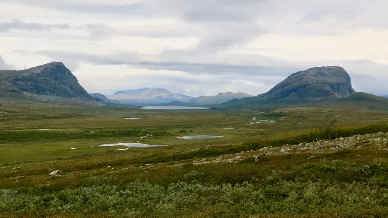 Vast, green valley with mountains and lakes, perfect for hiking trails Sweden.