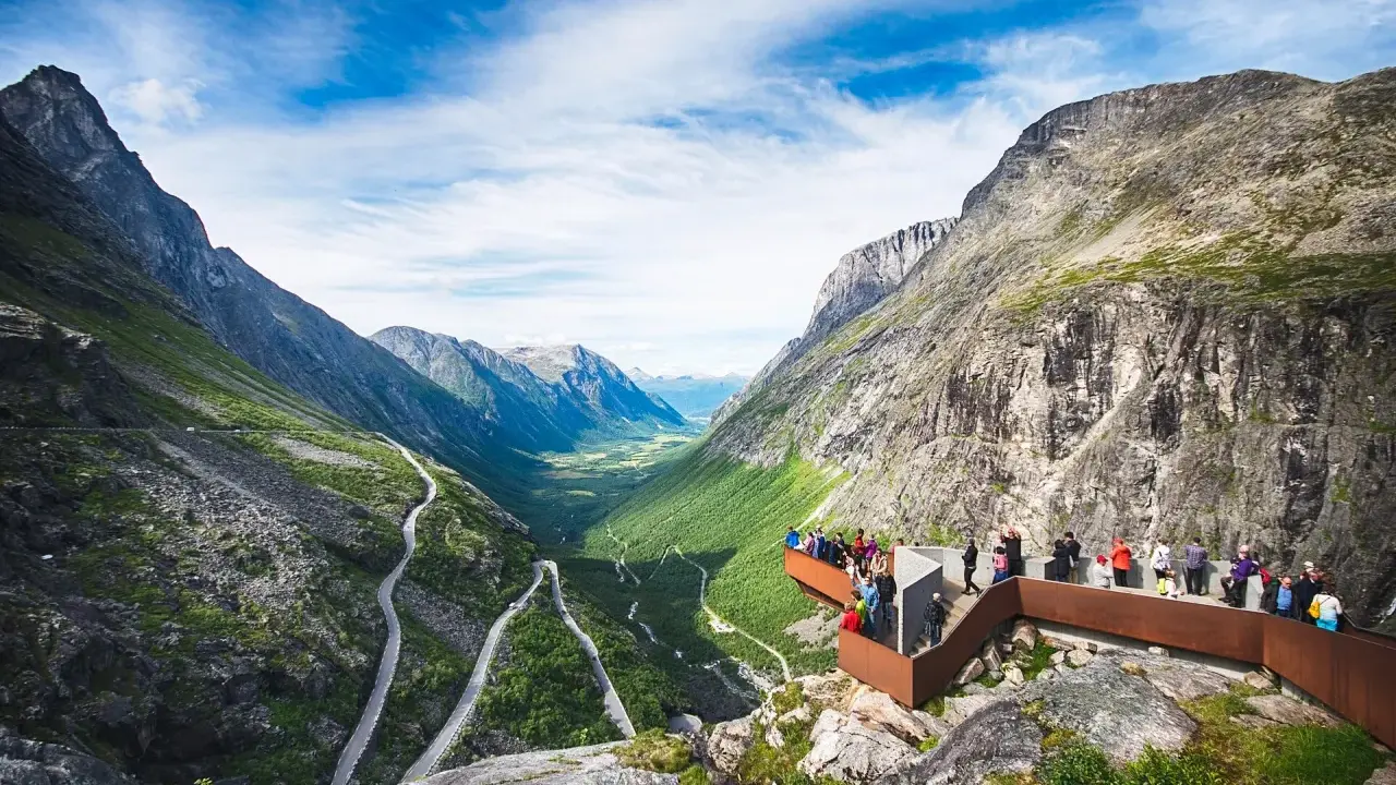 Besökare njuter av den dramatiska utsikten över Trollstigen i Åre, med en slingrande väg genom en grönskande dal.