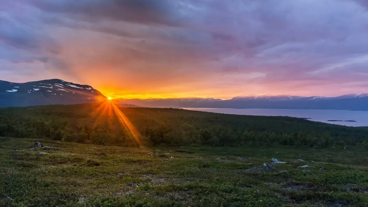 Midnattssol över Kiruna. Solen går inte ner bakom bergen, utan lyser upp himlen i ett magiskt skådespel.