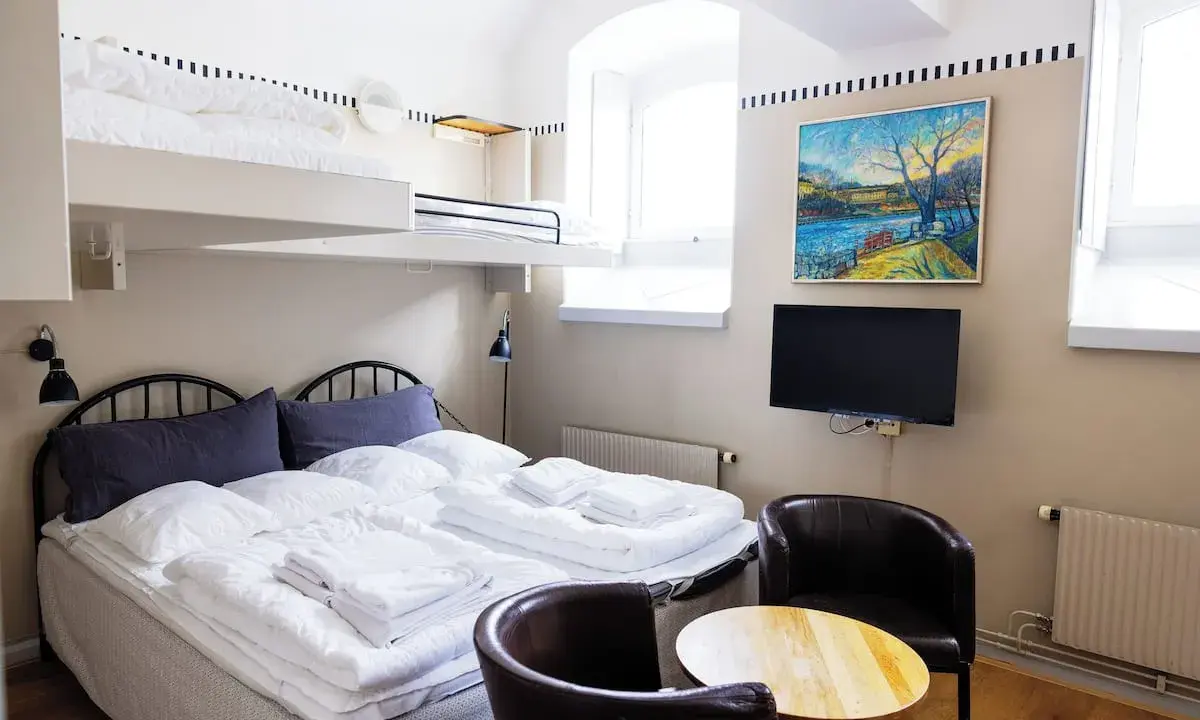 Ett mysigt rum på Langholmen Hotel med våningssängar, dubbelsäng, konst och TV.
