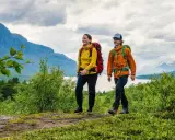 Två glada vandrare med ryggsäckar på en stig i fjällen. En perfekt plats att bo på efter en dag av vandring, kanske på ett STF vandrarhem.