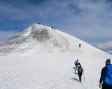 Vandrare klättrar uppför en snöig sluttning mot Kebnekaises topp. En bra packlista för Kebnekaise är avgörande för en säker och njutbar tur.
