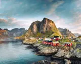 Röda fiskestugor vid en vik, med dramatiska berg i bakgrunden. En idyllisk vy som visar var ligger Lofoten.