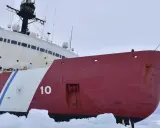 En röd och vit isbrytare, nummer 10, bryter sig fram genom isen.