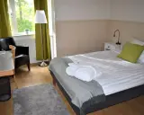 Ett mysigt rum på Wendelsbergs Hotell & Vandrarhem med en bekväm säng, fåtölj och skrivbord.