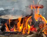 Matlagning över öppen eld, en härlig del av sportlov aktiviteter. Korv och mat i panna över flammande ved.