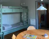 Enkel och mysig våningssäng i ett rum på STF Saltoluokta. En tidning och kortlek ligger på bordet.
