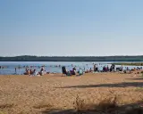 Folk njuter av solen och badar vid en strand, en perfekt plats för camping i Luleå.