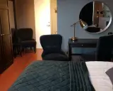 Ett modernt rum på Haparanda Stadshotell med en stor säng, skrivbord, spegel och bekväma fåtöljer.
