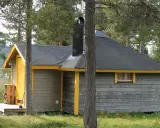 En mysig stuga för camping i Kiruna, omgiven av skog och med en sjö i bakgrunden.