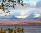 Vacker vy över Lapporten i Abisko, Sverige. Snöklädda berg reser sig över en höstfärgad tundra vid en sjö.