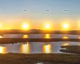 Solens resa över sjö och skog i Sverige under midnattssol.