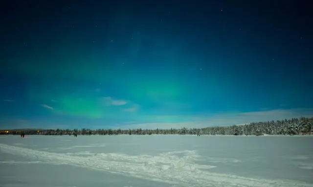 Norrsken dansar över ett fruset hav i Sverige. Snö och stjärnor lyser upp den kalla natten.
