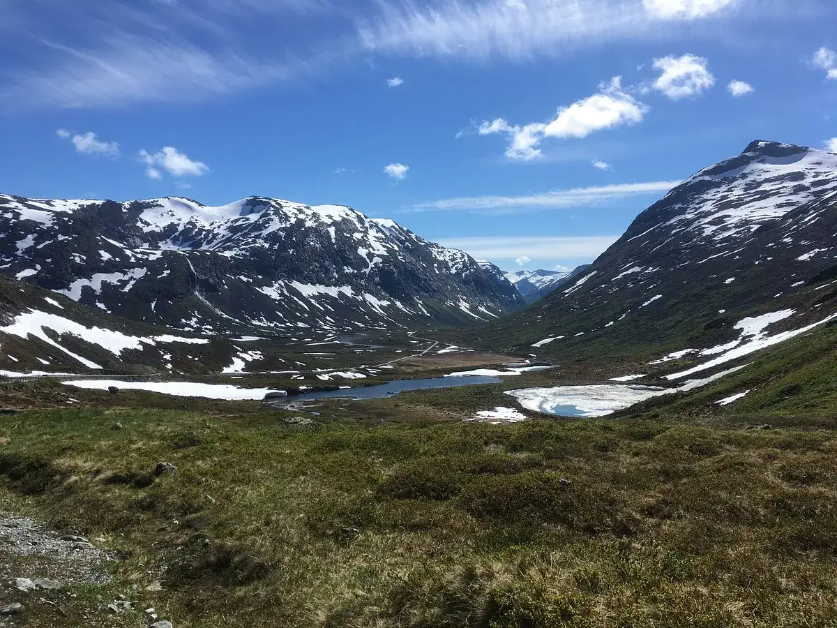 Vacker dalgång med snöklädda berg, en sjö och grönskande sluttningar. Känns som att stå vid trollväggen.