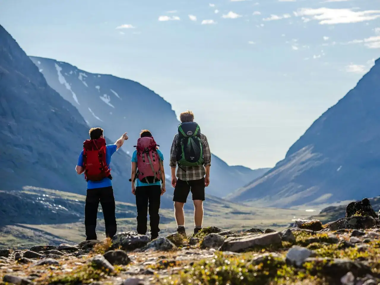Vandrare pekar mot fjällen vid Abisko, med Kebnekaise i sikte.