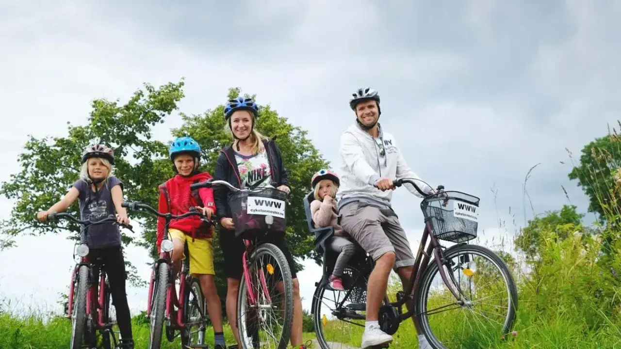 Familj på cykelsemester med barn. Två vuxna och tre barn på cyklar i naturen.
