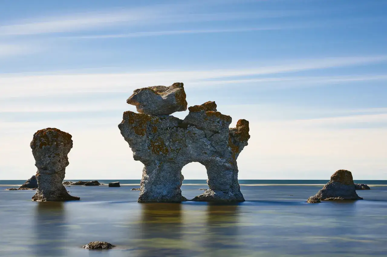 Raukar, dessa måsten på Gotland, reser sig ur havet under en blå, molnig himmel.