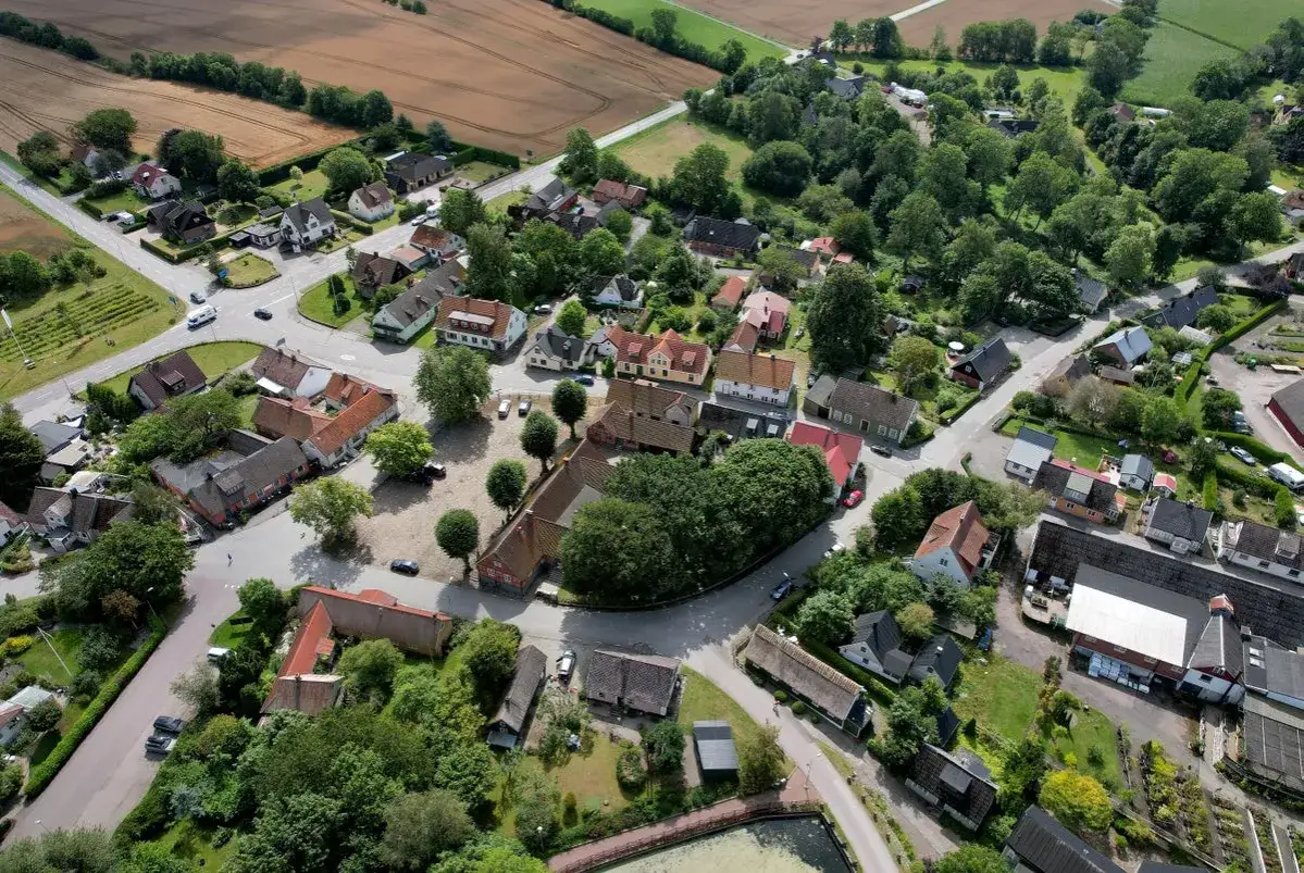 Vy över ett svenskt samhälle med röda tegeltak och gröna träd. Ett lugnt och idylliskt landskap i Skåne Tranås.