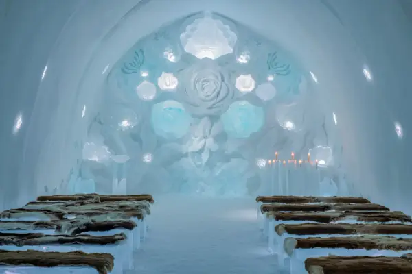 Vacker iskyrka i ett igloo hotell Sverige. Bänkar av is med renskinn, isrosor och levande ljus skapar en magisk atmosfär.